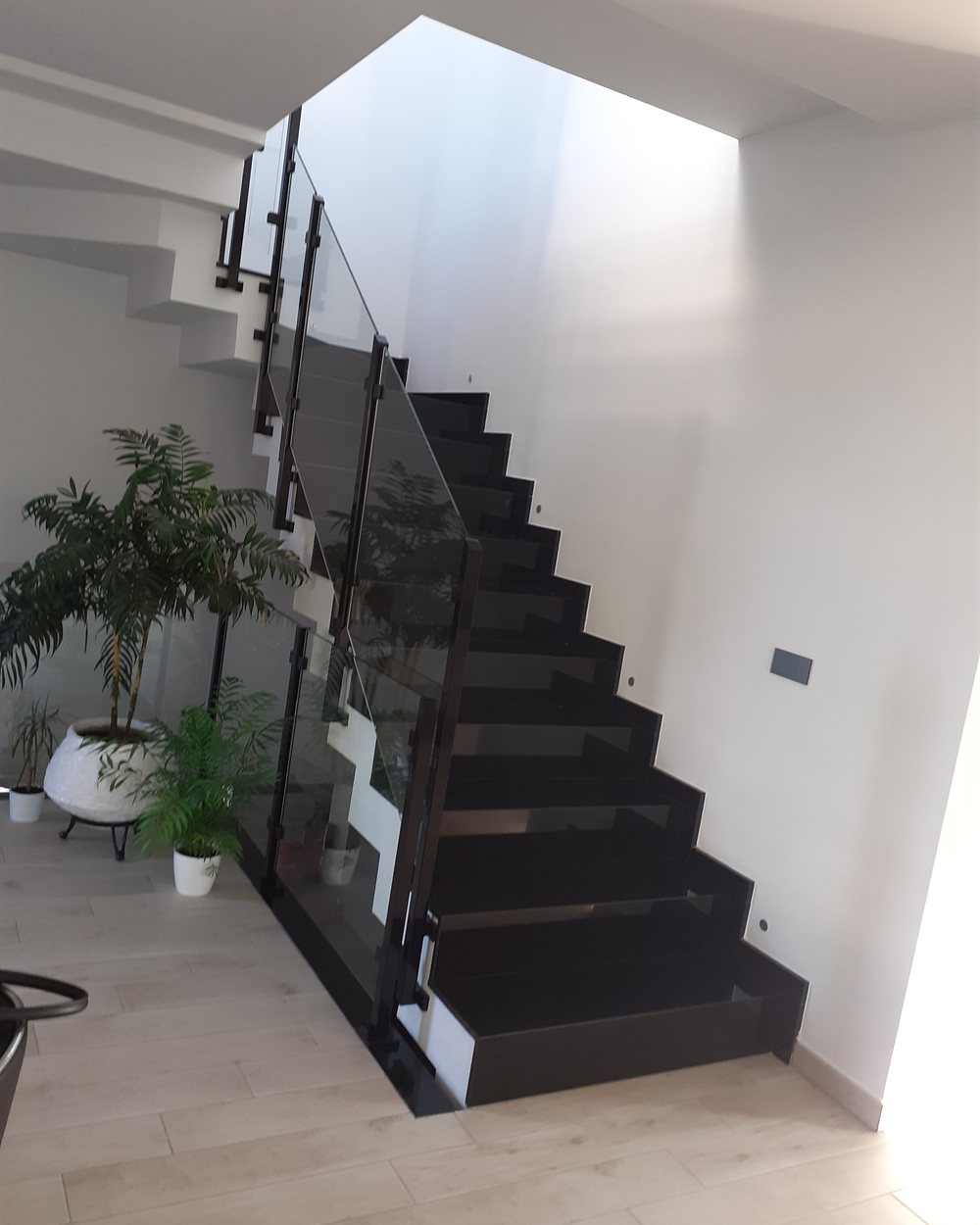 Escalera interior con estructura metálica y barandilla de vidrio en una vivienda proyectada por CAC Arquitectos