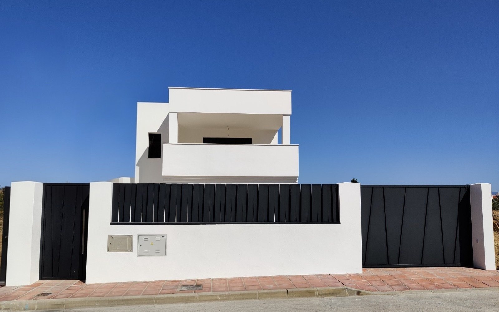 Fachada de vivienda adosada de obra nueva, con cerramiento de lamas metálicas oscuras, proyectada por CAC Arquitectos