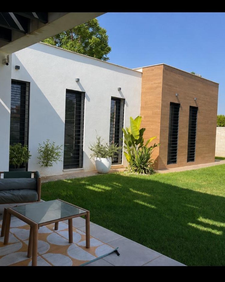 Fachada de vivienda unifamiliar aislada de una planta, con volumen revestido en madera y ventanales verticales, obra de CAC Arquitectos